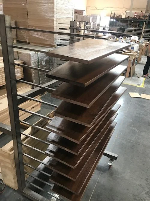 Wooden panels stacked on a metal rack in a workshop or factory setting.
