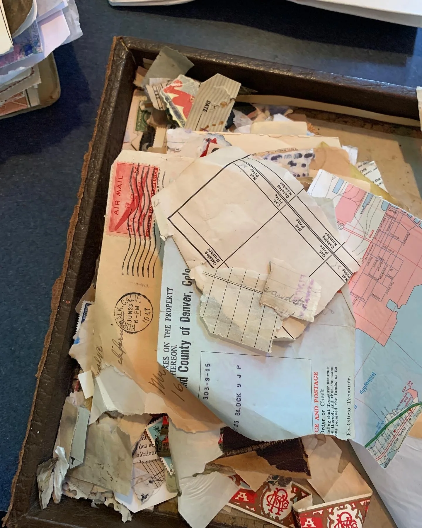 A box filled with vintage paper scraps for collage in a vintage travel journal.