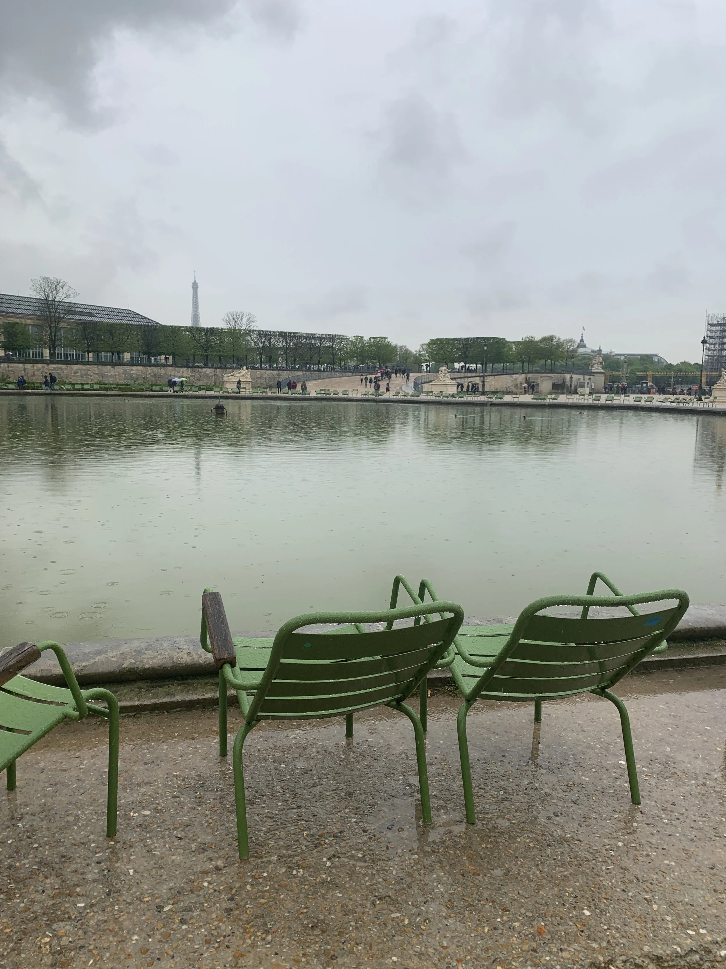 The famous green chairs next to a pond in the Tuileries Gardens, Eiffel Tower in the distance, Paris, France.