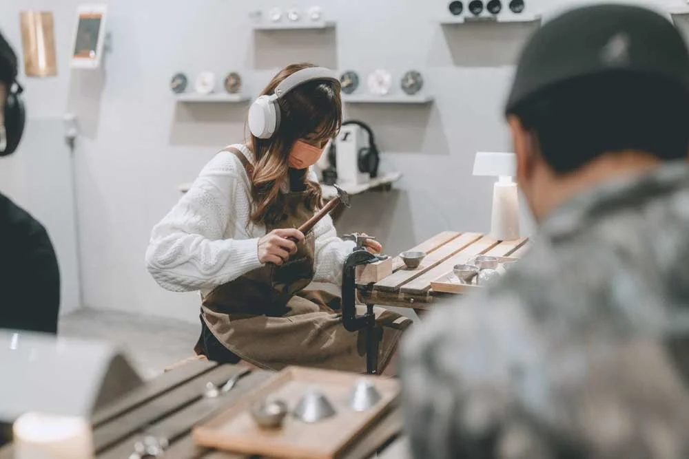A long hair women wearing a headphone crafting sake cup on a wooden table