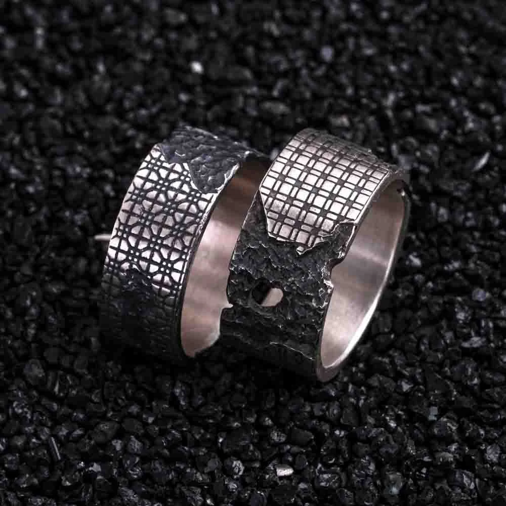 Close-up of the 2073 City Decay Collapse cuff with a cracked mosaic pattern, placed on black coal