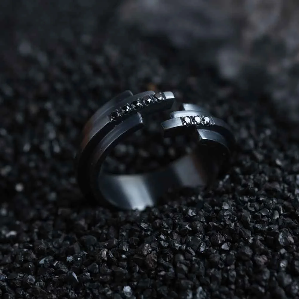 Close-up of a black ring from the 2073 City Decay Glitch collection, placed on black coal