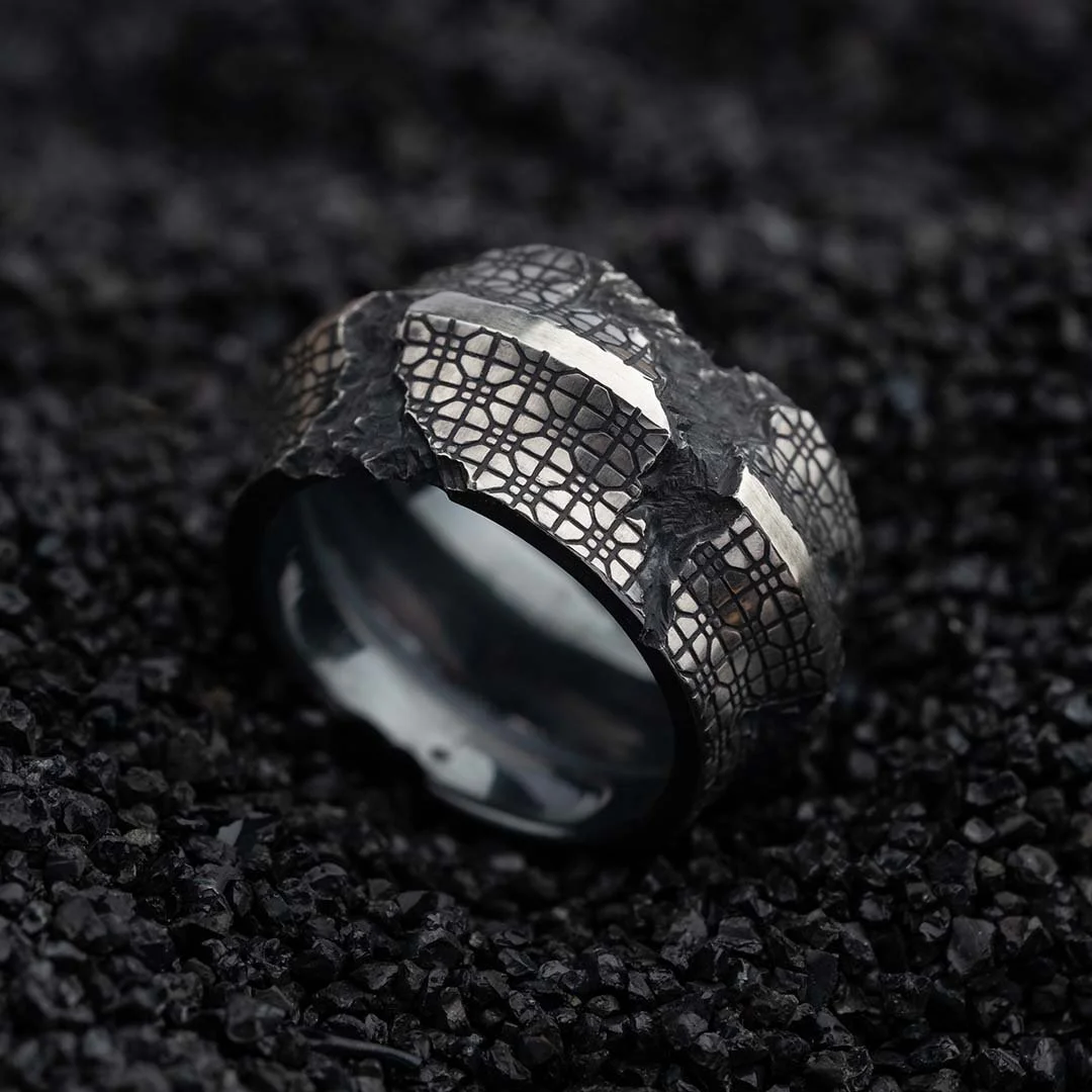 Ring from 2073 City Decay collection with a cracked mosaic pattern, placed on black coal
