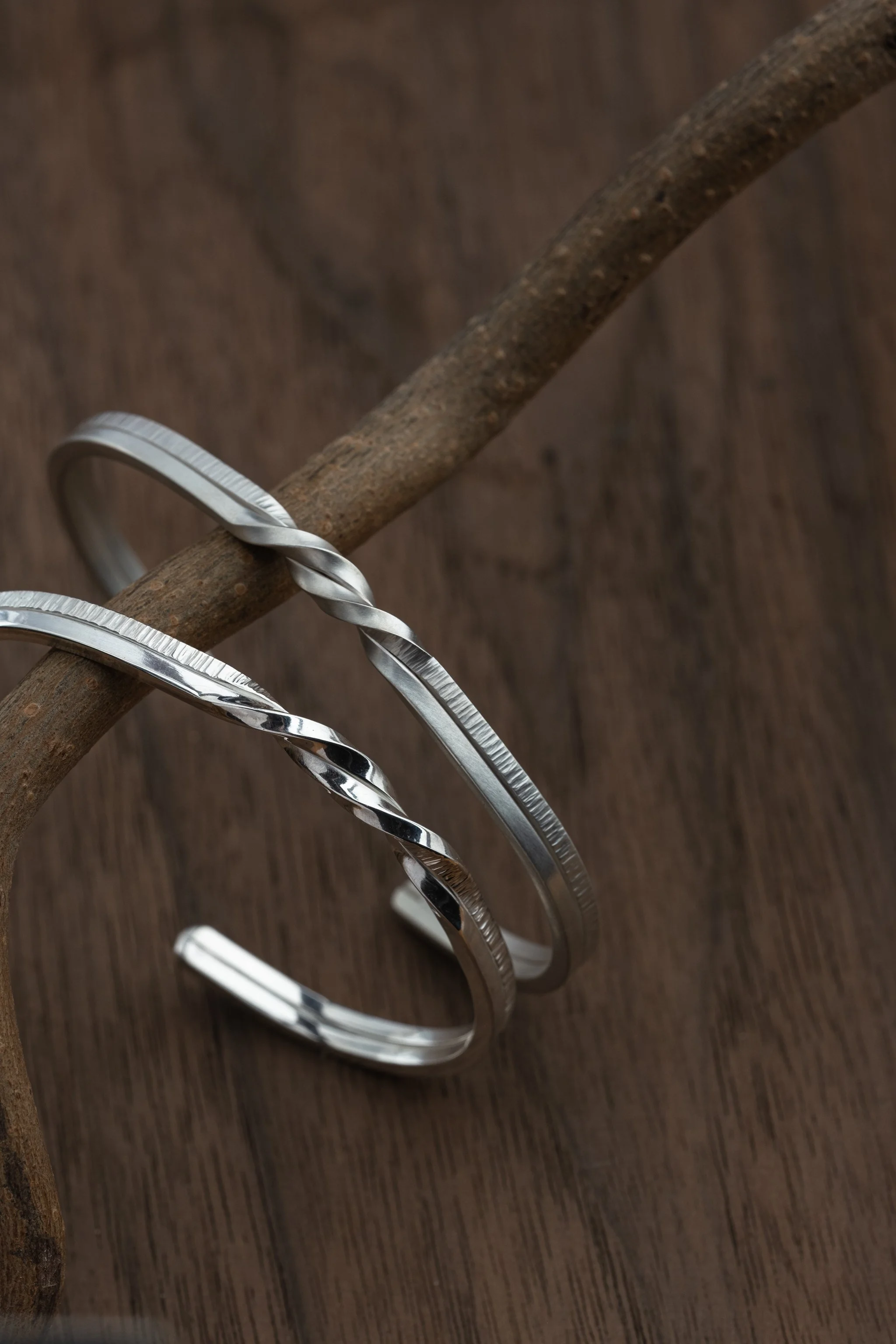 Two Sliver Twin Souls Couple Bracelet placed on wood