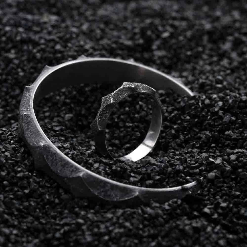 Close-up of 2073 City Decay lost star 05 Ring and Bracelet on black sand