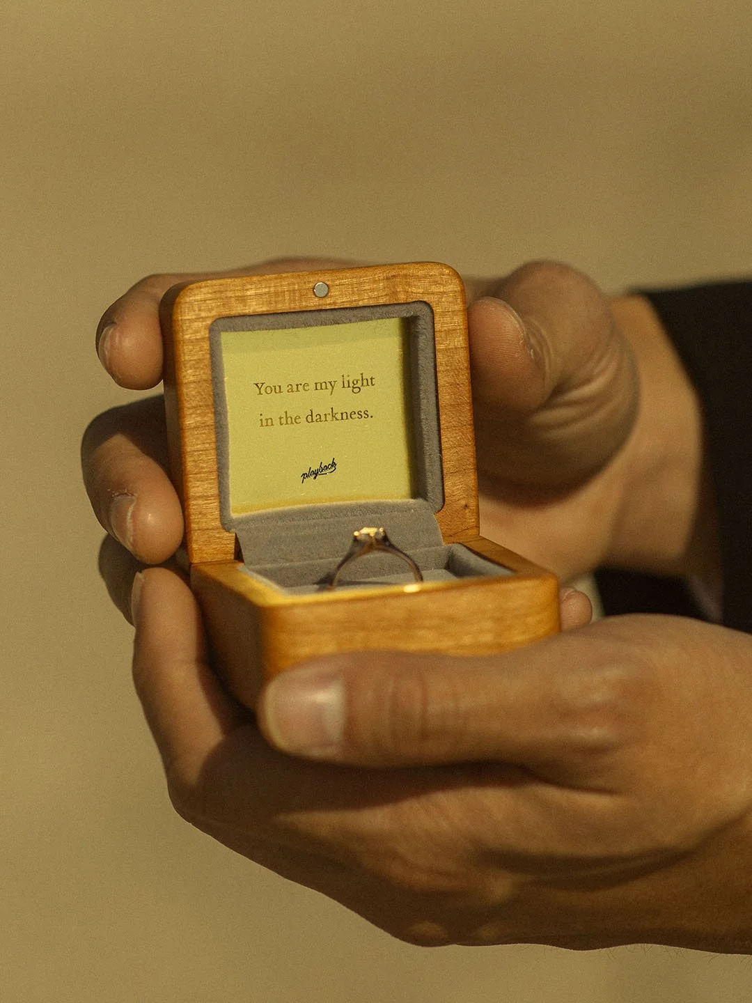 Close-up of man holding the 18k diamond engagement ring in the wooden ring box