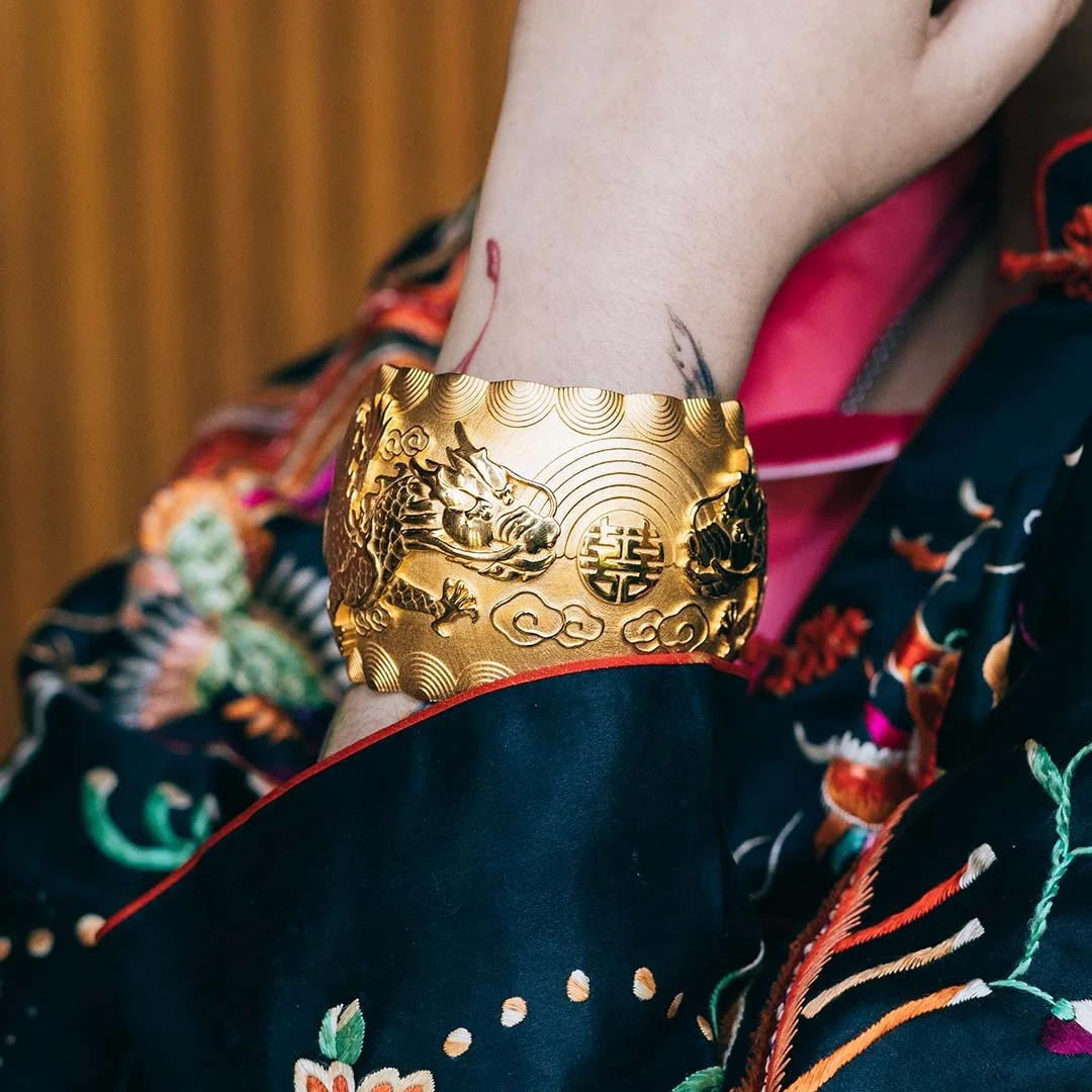 women wearing black chinese traditional gown with tattoo wearing a yellow gold dragon pattern bangle
