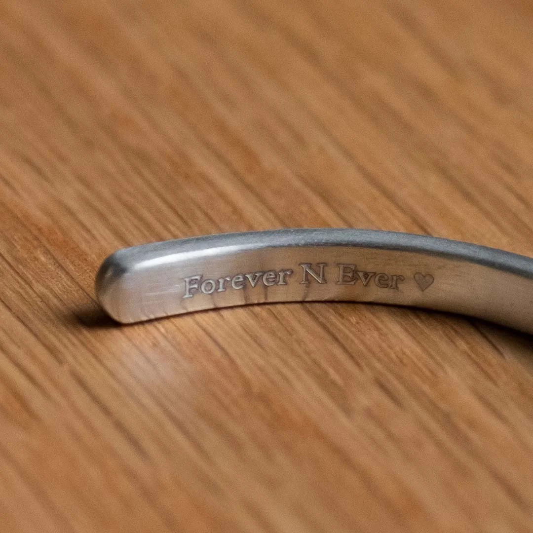 A bracelet engraving example with wording " Forever N Ever" on a wooden table