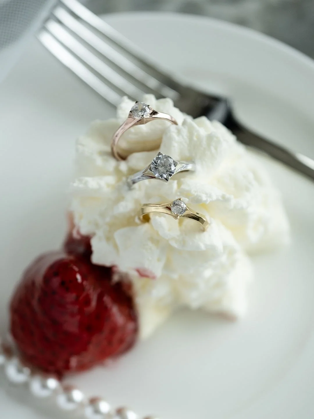 Three Love Nova Engagement Rings hide inside the fresh cream on a white plate with a fork next to it
