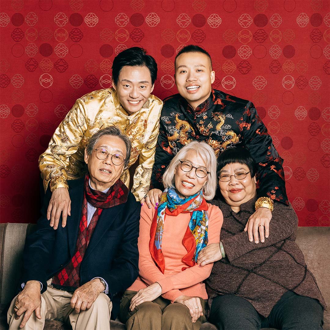 A Family photo taken under the red pattern cloth, grooms wearing The Proud Pair Collection on their hands