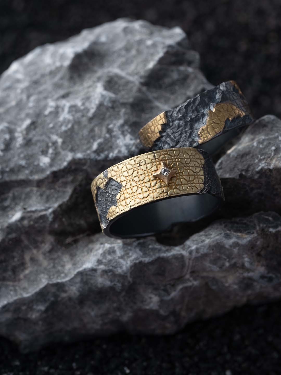 Top view of two 2073 City Decay memento ring in gold material showing different angel of the ring placed on the rock