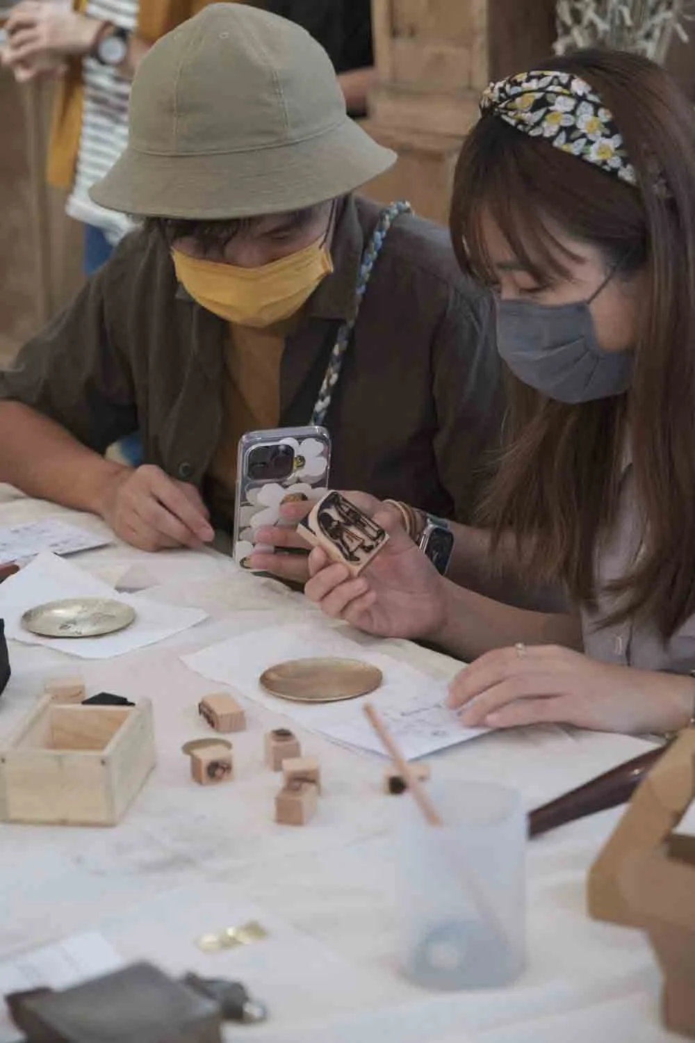 a women and a man stamping the brass plate on the wooden table in per se workshop event