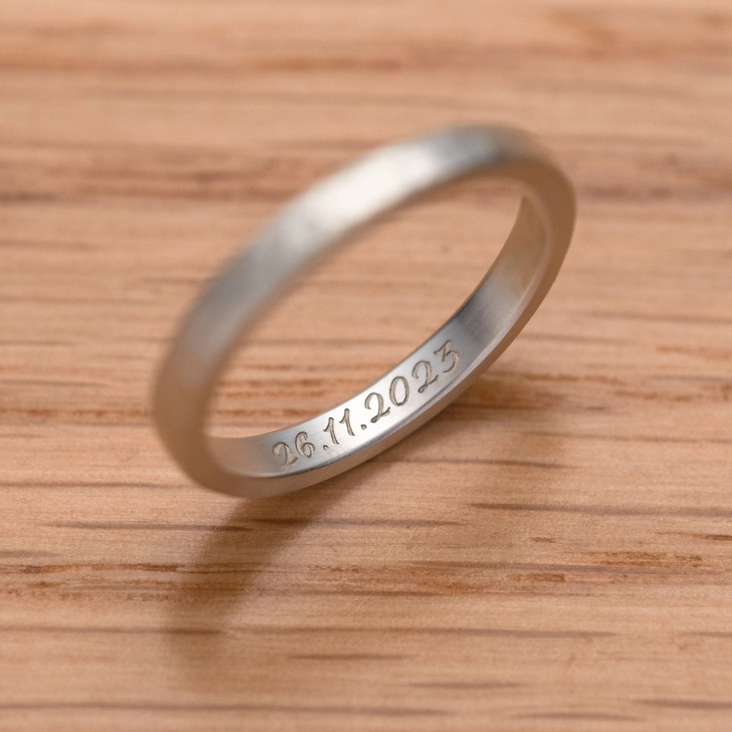 A sliver ring engraved sample on wooden table