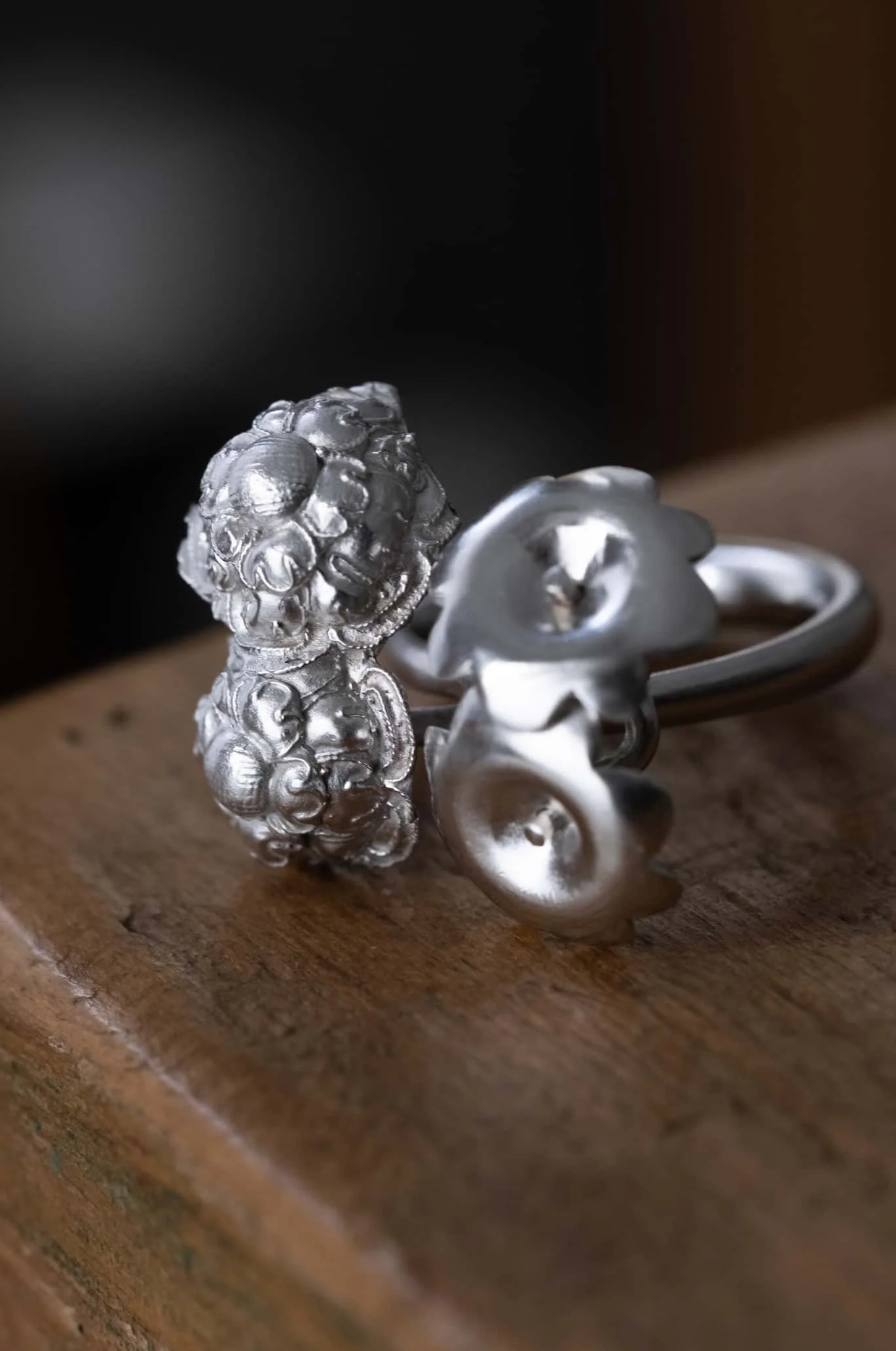Redesigned Sliver ring with flower shape from hairpin showed on wooden table