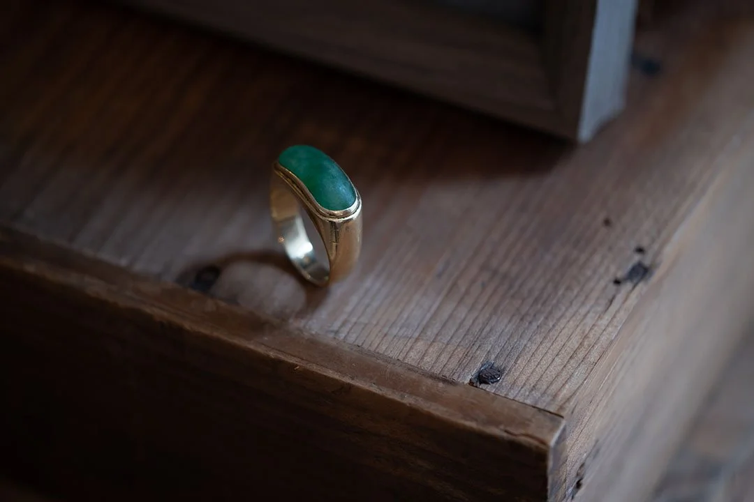 A green gem stone Relic from client's Father on the wooden table