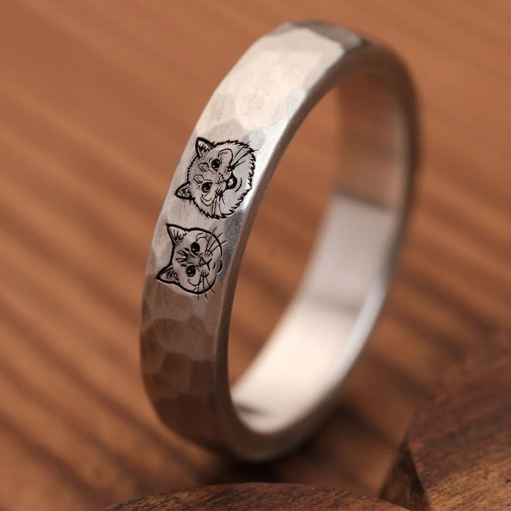 Close-up of two cat portraits engraved on a hammered silver ring