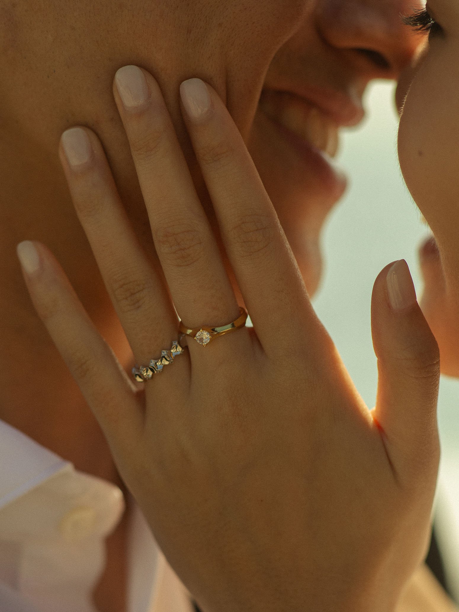 A women's hand wearing Nova of Dream Engagement Ring Collection touching man's face