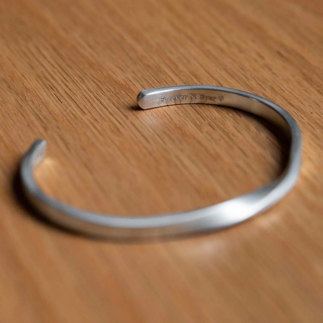 A bracelet engraving example with wording " Forever N Ever" on a wooden table