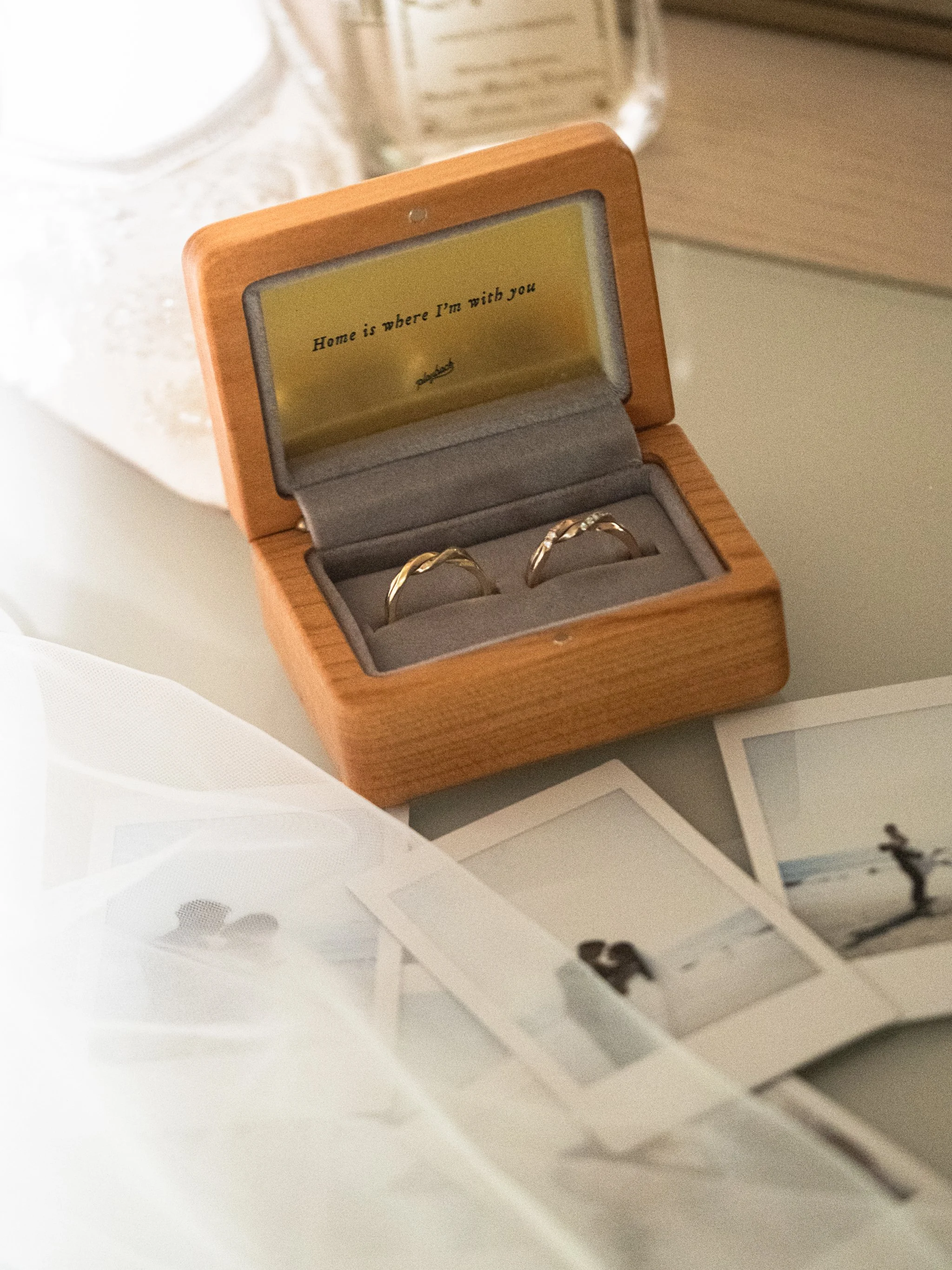 Two Twin Souls couple ring in the wooden ring box placed with three polaroid on glass table