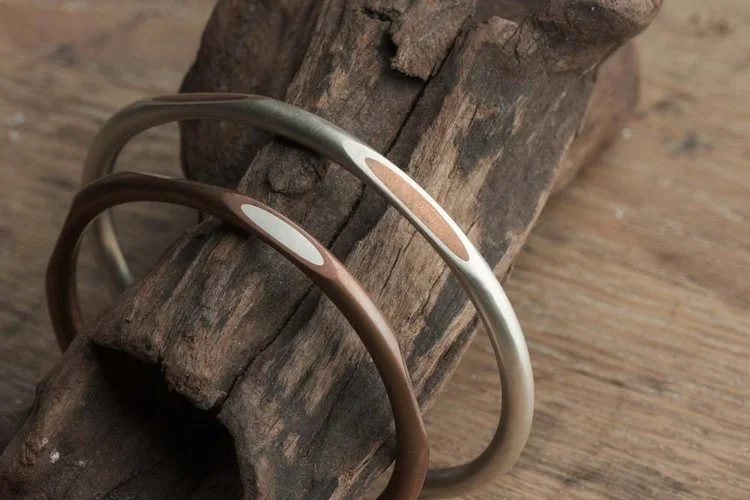Two Driftwood Bracelets with copper and silver material on a wood