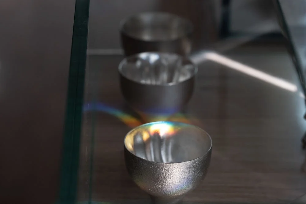 Few tin sake cup with rainbow lighting on a wooden table