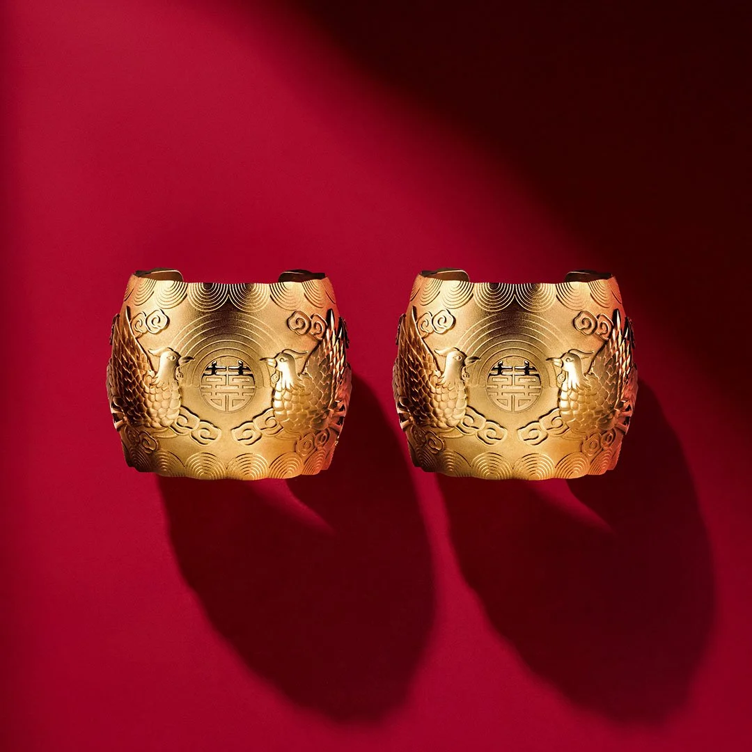 two gold phoenix bangle from Proud Pair Collection on the red plain background