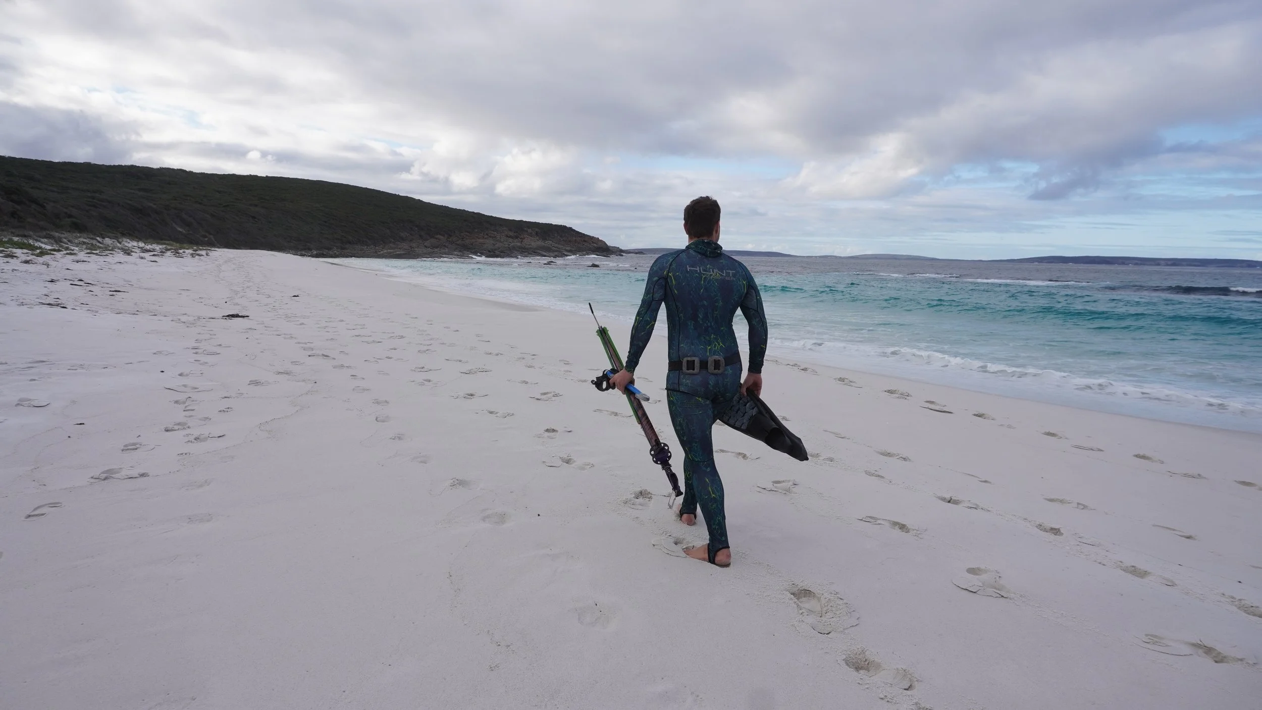 Xande wheldon walking on the beach holding his spear fishing gear