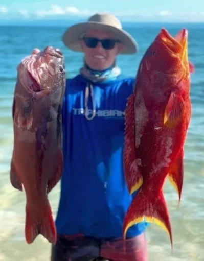 Guy in triphibian adventures fishing shirt holding a coral trout