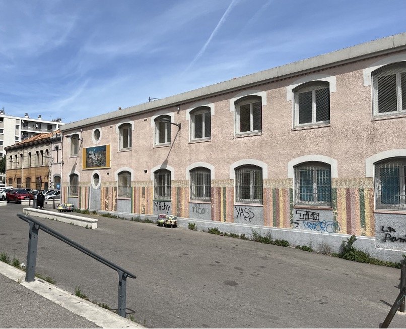 The École élémentaire Parc Bellevue in Saint-Mauront, Marseille: a pink two-storey school building with graffiti tags along its lower wall. Rue Lise de Baissac should run alongside it, but no street sign was to be found.