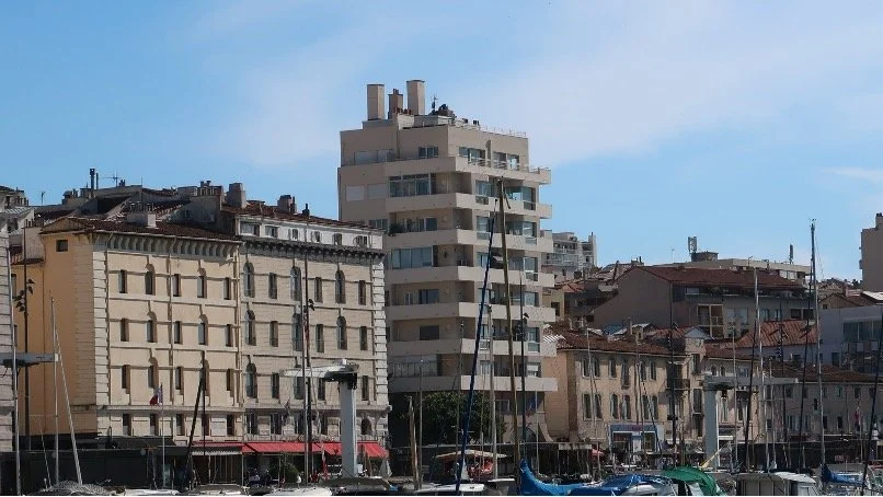 Lise de Baissac's building seen from across the Vieux Port, from the ferry, among the quayside houses and the masts of moored boats.