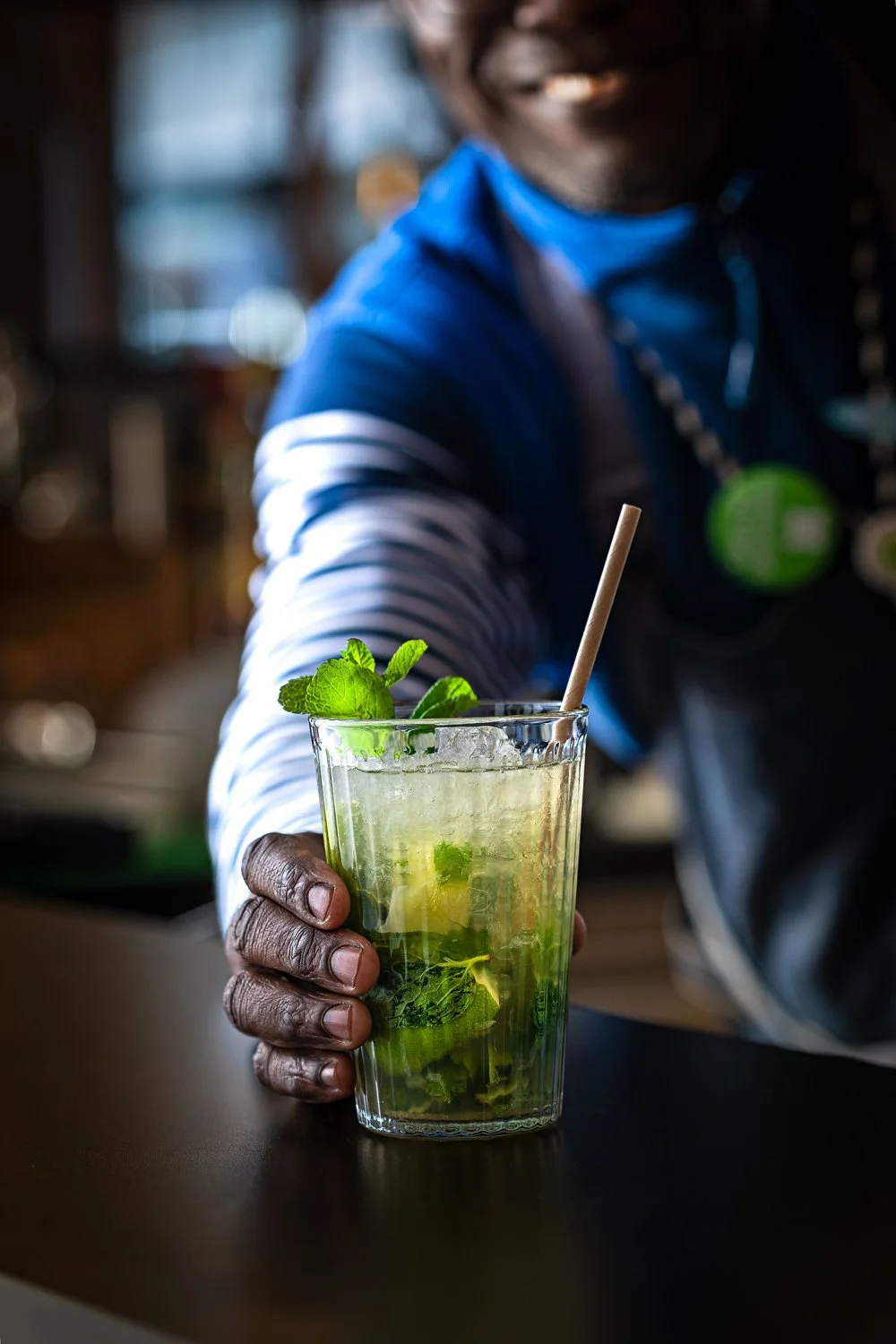 Pessoa segurando um copo de mojito com menta e canudo.