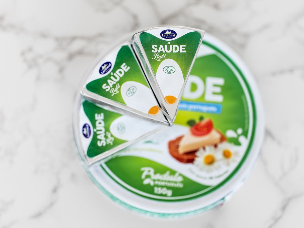 Queijo processado em triângulos com embalagem verde, marca "Saúde Light" da Lactimar, sobre uma mesa de mármore.