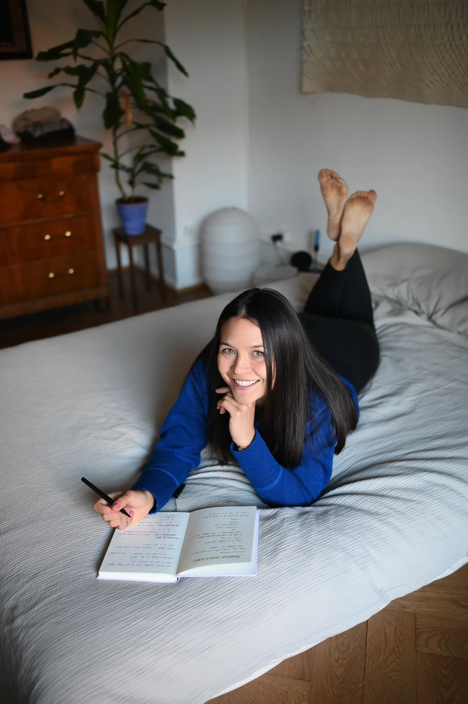 Smiling girl on a bed with a notebook