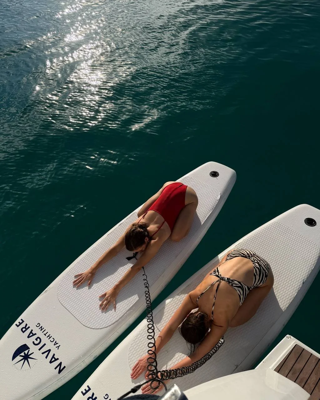 2 girls on sup boards doing yoga