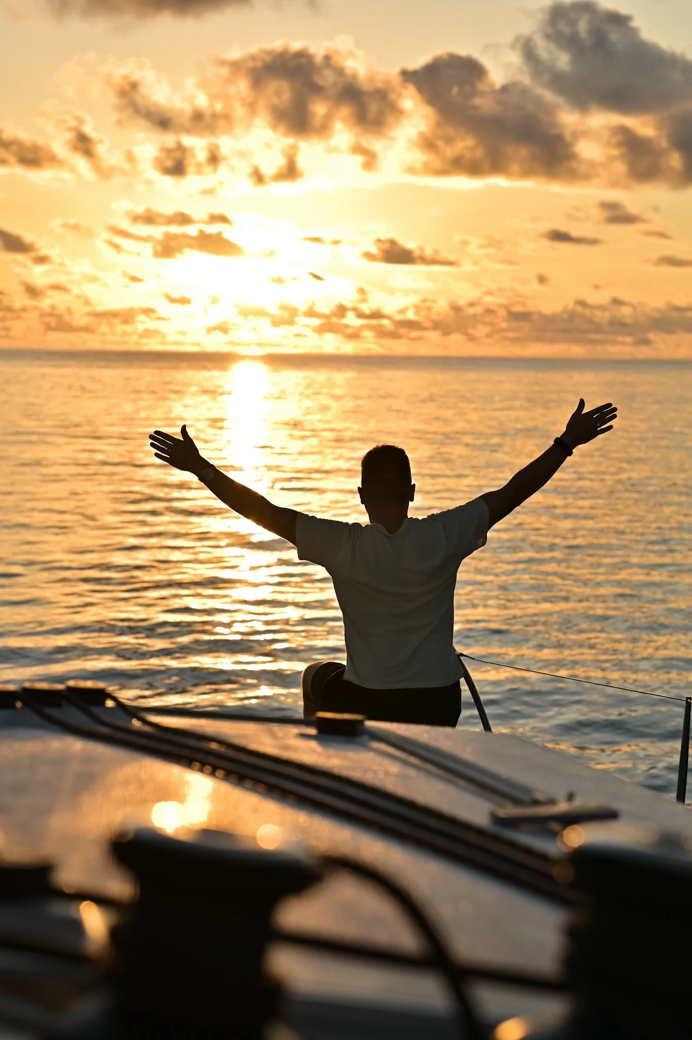 Man sitting on a catamaran in front of the sunset