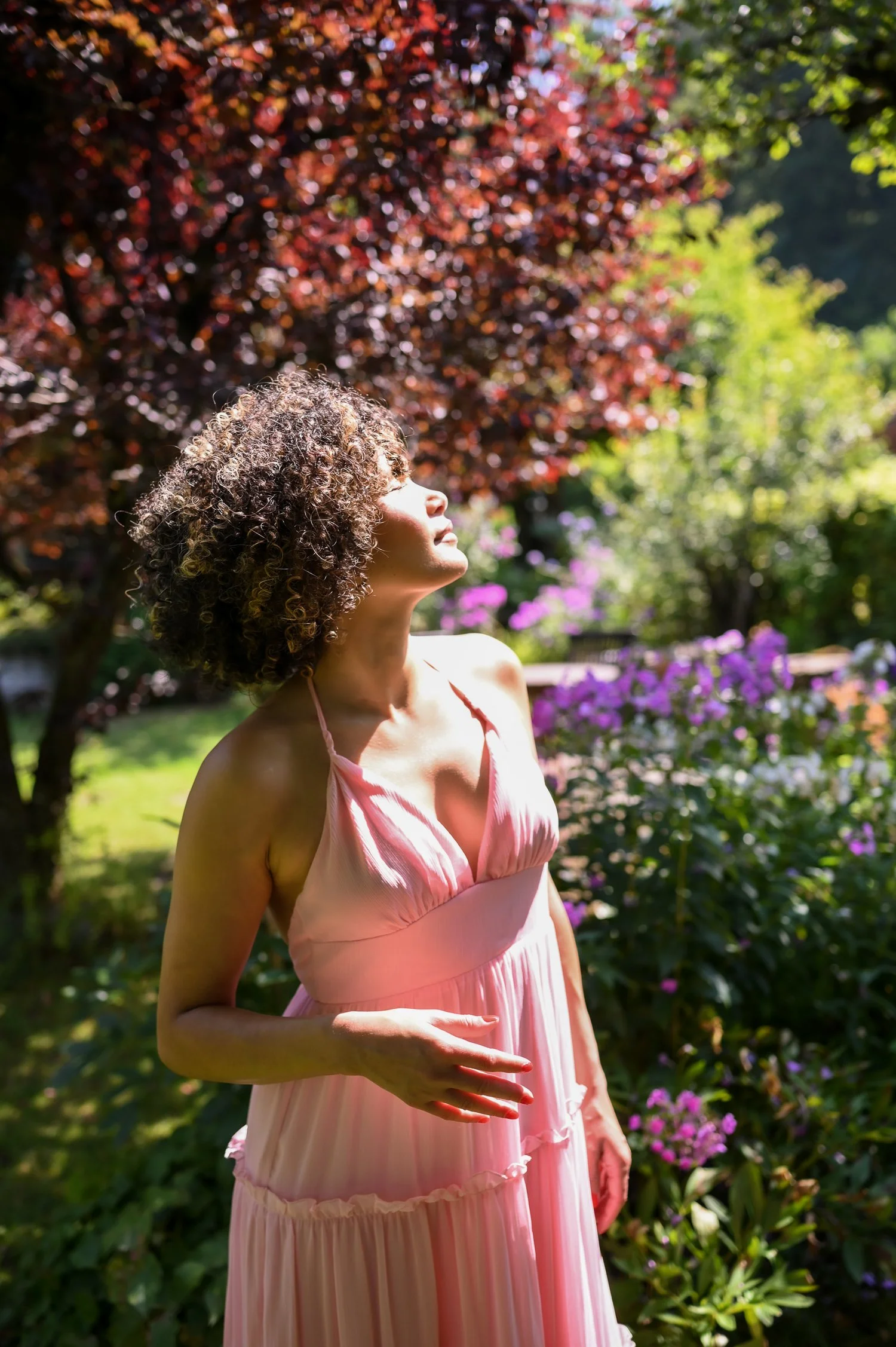Young girl with gorgeous curls standing beside a magnificent tree in a serene environment