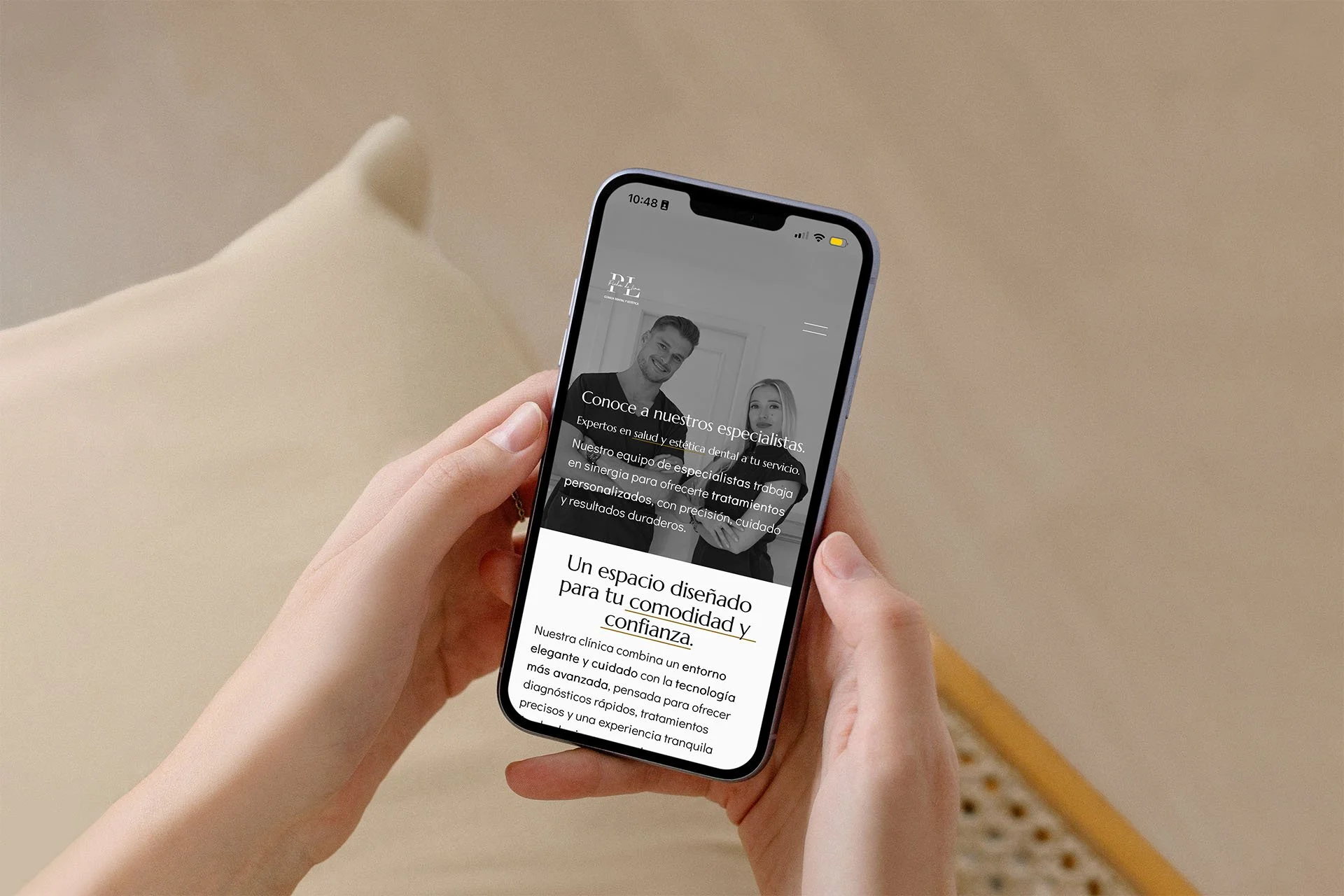 Person holding a smartphone displaying a dental clinic webpage with a black and white photo of a smiling man and woman.