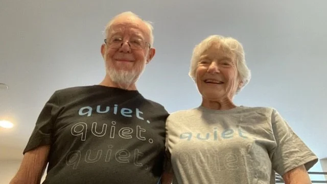Trees bend over a still river with snow covered banks at dusk