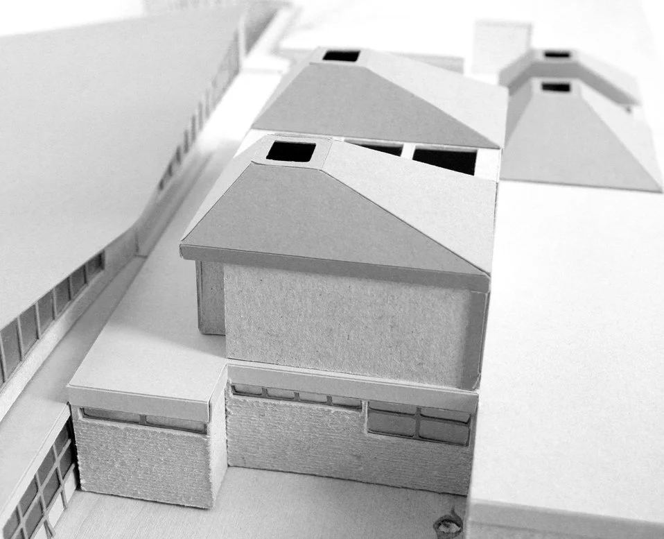 Grey card architectural model of a school with pyramid-shaped roofs to the individual volumes and skylights