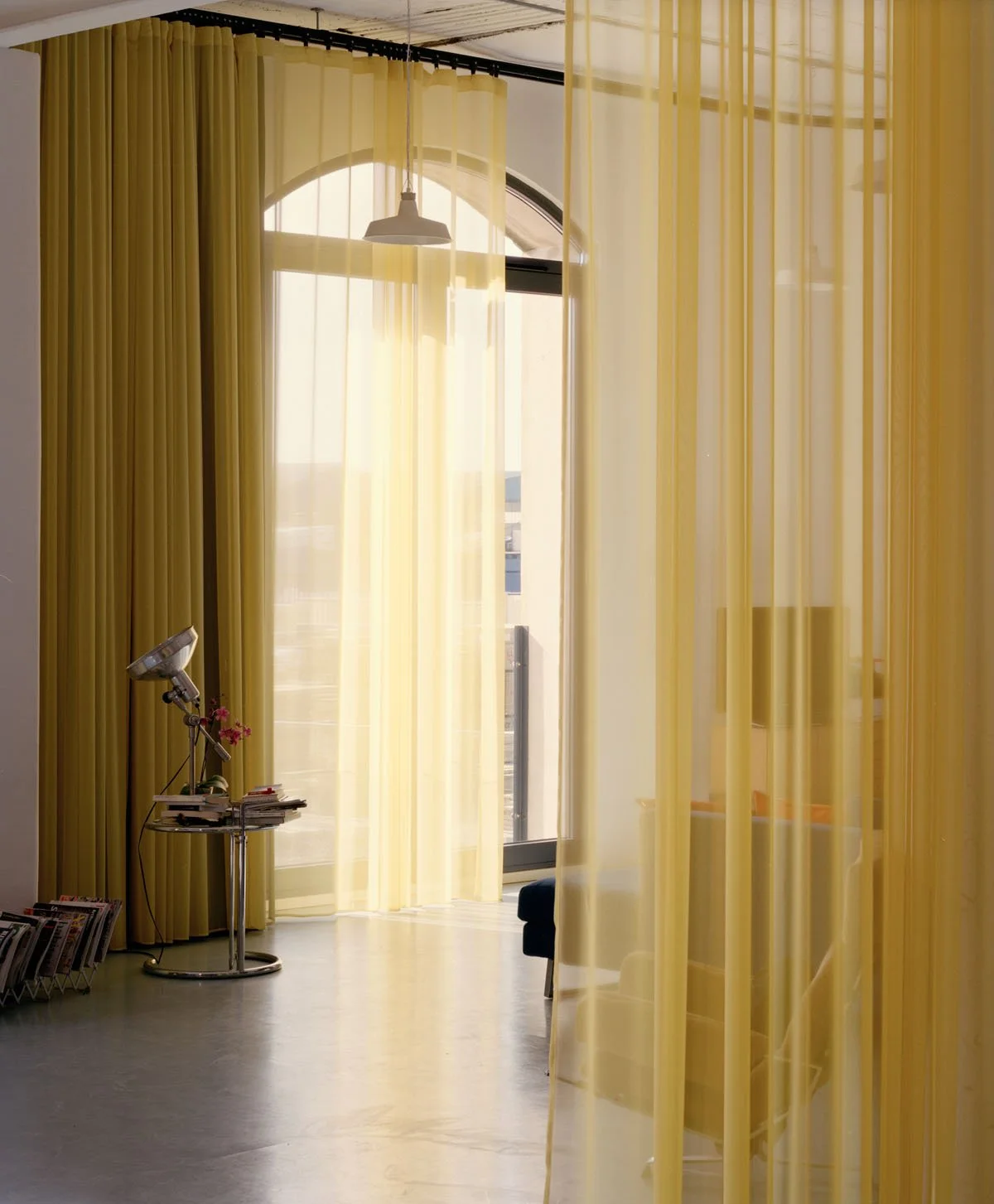 Interior design detail of translucent yellow fabric curtains subdividing a workspace and a polished concrete floor