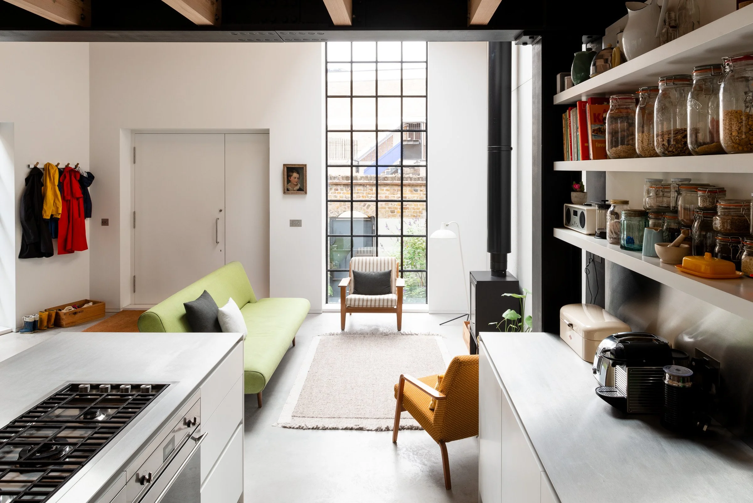 Converted Gin Distillery with large warehouse crittall window, exposed Douglas fir timber joists and black steel beams with a polished concrete floor, stainless steel kitchen worktops, open pantry shelving, wood burner and light-filled interior