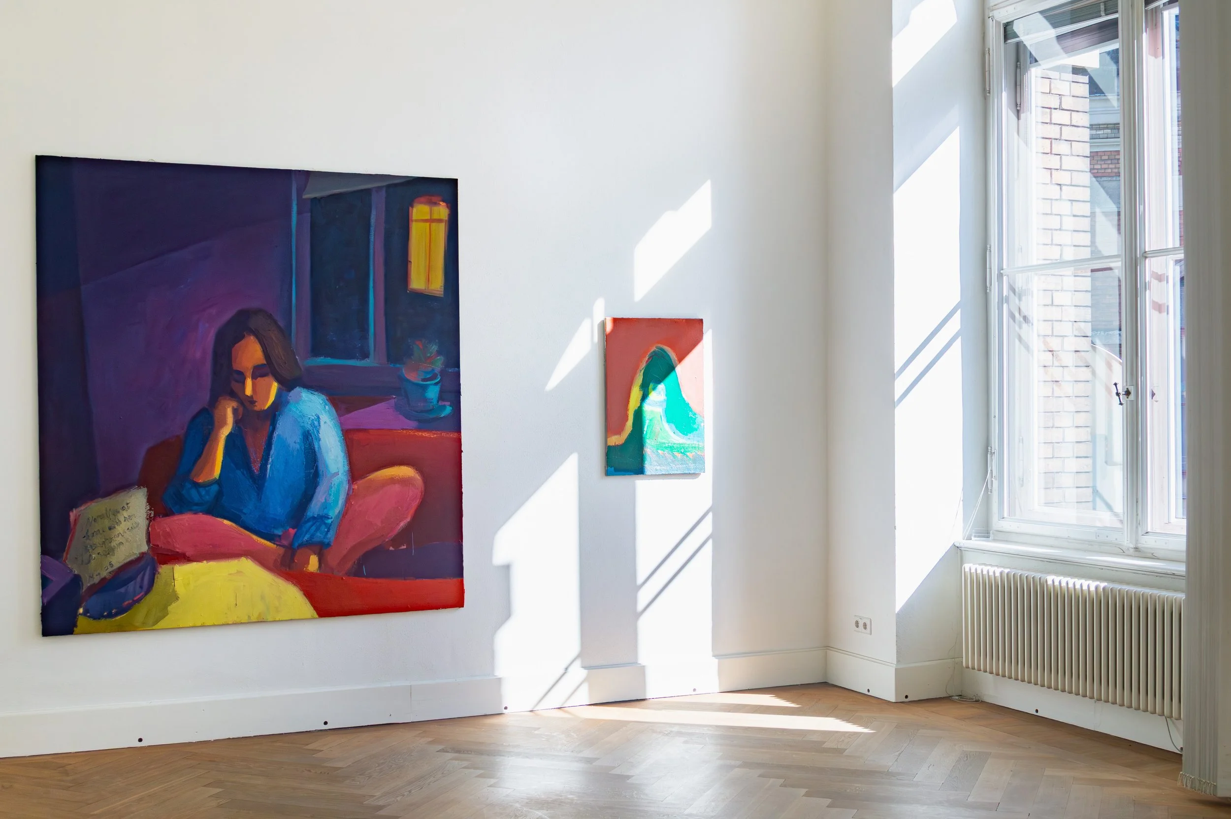 Malerei Quang Minh Tran Diplom an der Hochschule für Bildende Künste Dresden.  Zwei Gemälde hängen an einer weißen Wand in einem hellen Raum mit Holzboden. Das größere Gemälde zeigt eine sitzende Frau, das kleinere ein abstraktes Bild.