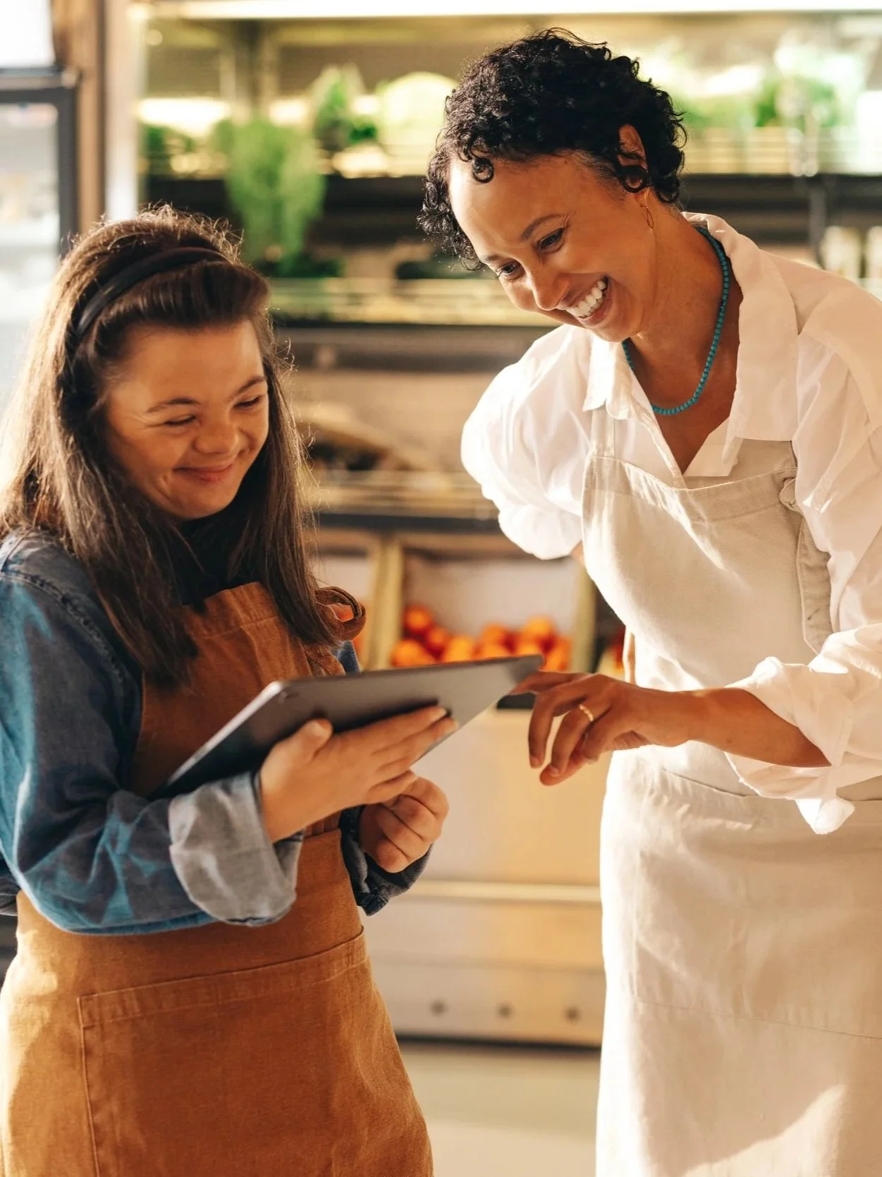 Employee receiving hands-on guidance from a supervisor while using a tablet at work.