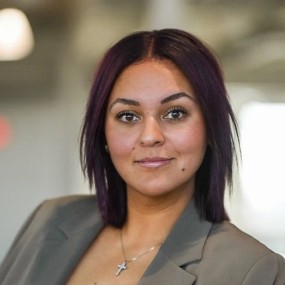 Professional portrait of Reese Niu wearing a gray blazer in an office setting.