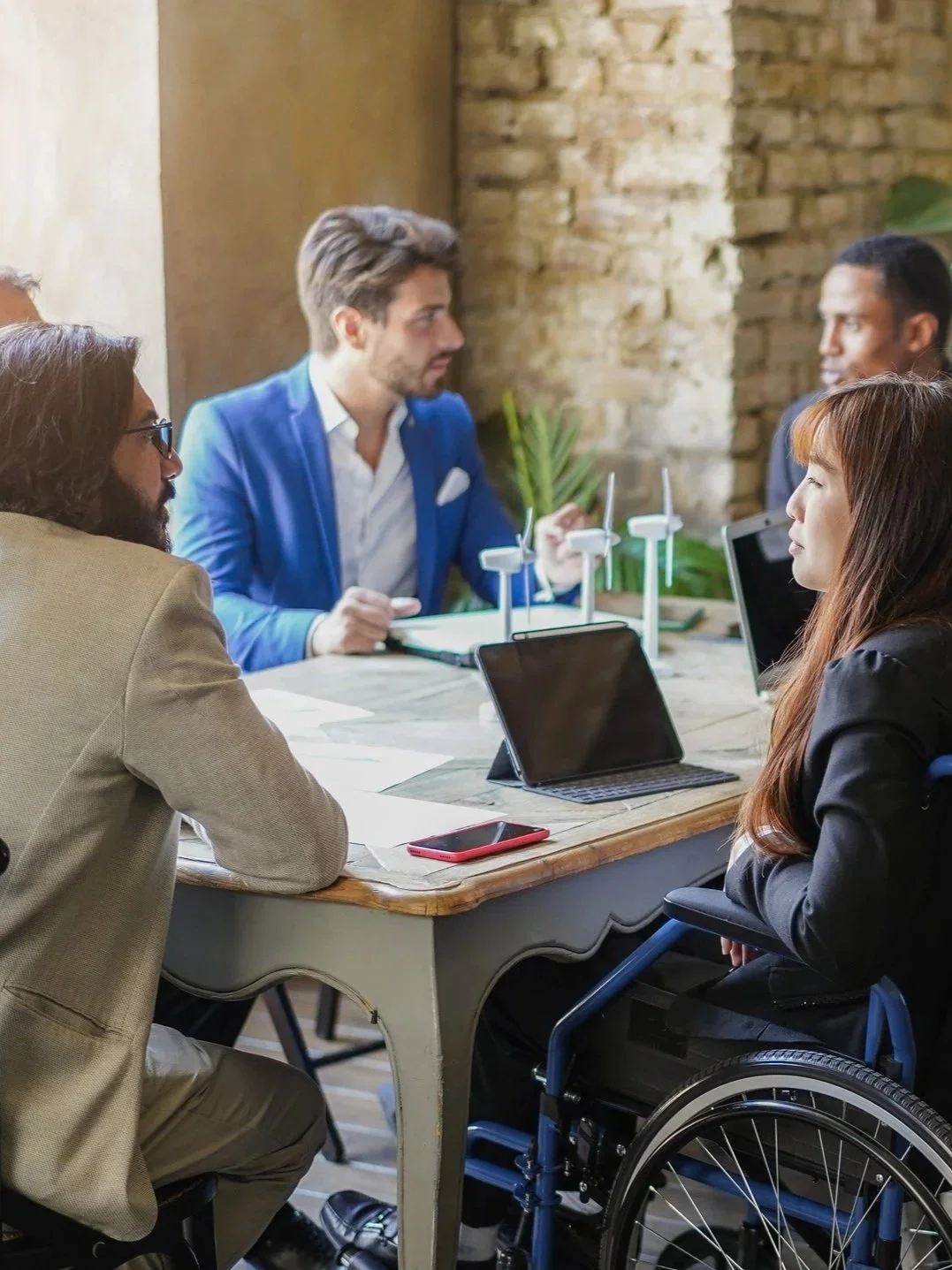Diverse team collaborating in a meeting, including a professional using a wheelchair.