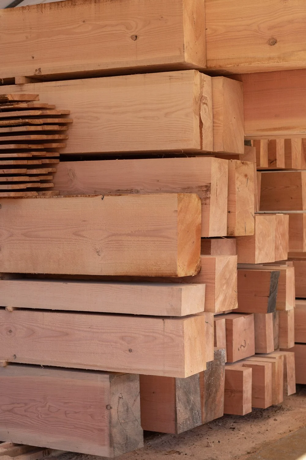 Stacked cut and unfinished wooden beams or planks stored in a lumber yard.