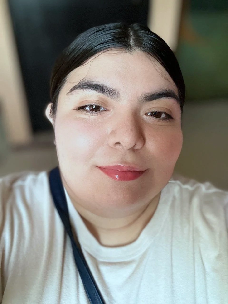 Retrato de una mujer con cabello negro, cejas gruesas, labios rojos y piel clara, sonriendo ligeramente.