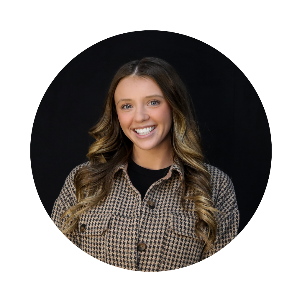 A young woman with long wavy hair smiling against a black background.