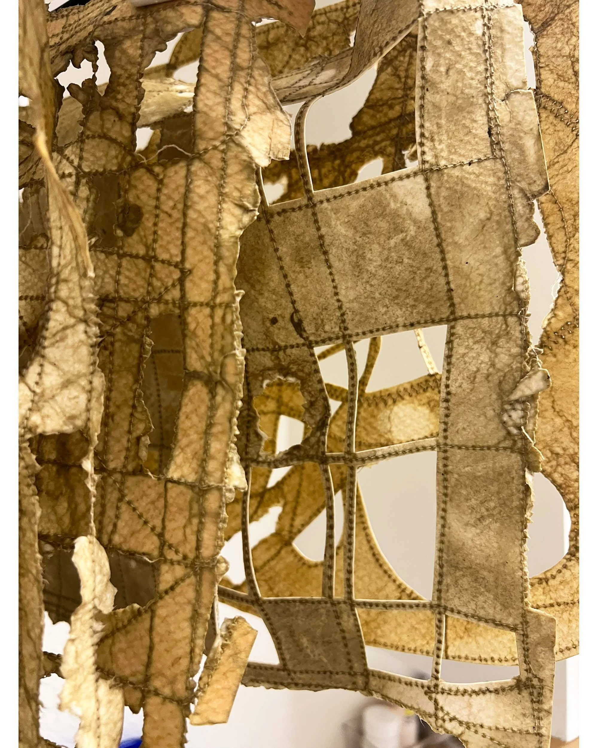 Close-up of a worn, tattered fabric and wire structure, possibly part of an old sculpture or art piece.