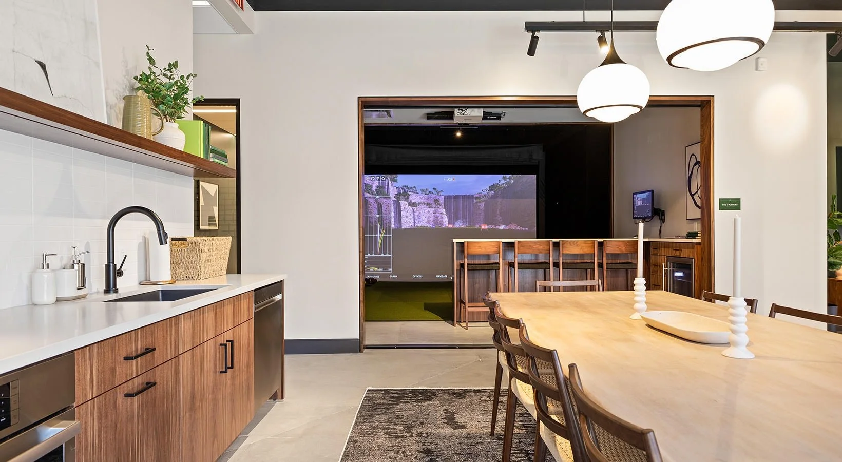Interior of a modern conference room with a large wooden table, candles, and a large screen displaying a nature scene in the background.
